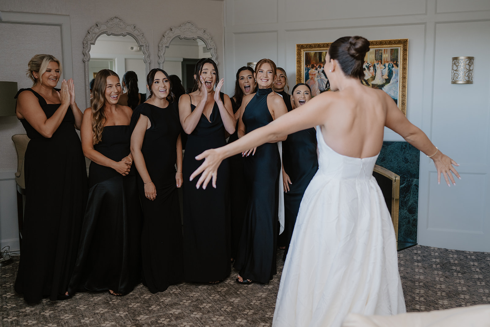 Bridesmaids reacting with gasps of joy during a first look with the bride in her gown.